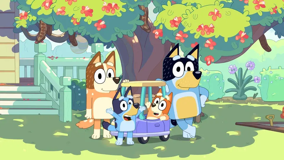 In a vibrant garden under a flowering tree, four cartoon dogs from the show 'Bluey' are gathered. Bluey, a small blue dog…