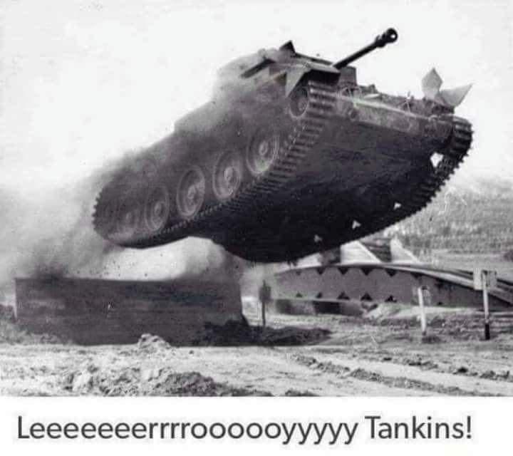 A black and white photo shows a tank mid-air, appearing to levitate or jump over a structure, with smoke billowing from its…