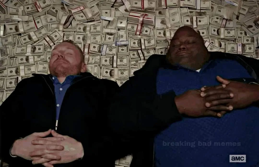 Two men are lying down with their eyes closed, surrounded by a wall covered in stacks of US dollar bills. The man on the…