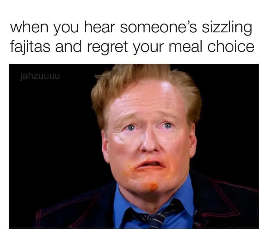 A close-up image of Conan O'Brien with a distressed, regretful expression, sauce smeared on his face and chin, wearing a…