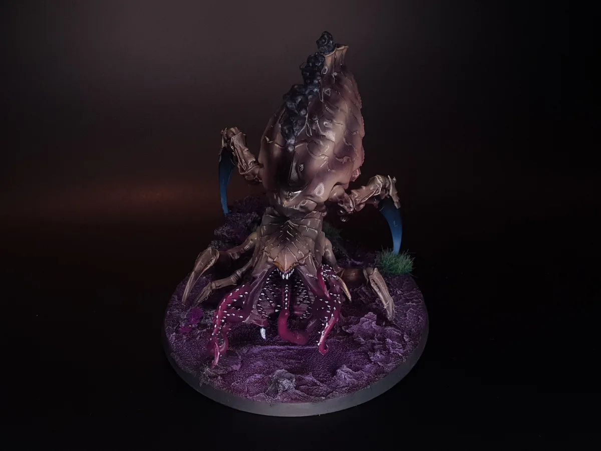 A highly detailed, painted miniature of a monstrous, multi-limbed creature with a bulbous, textured body, blue curved…
