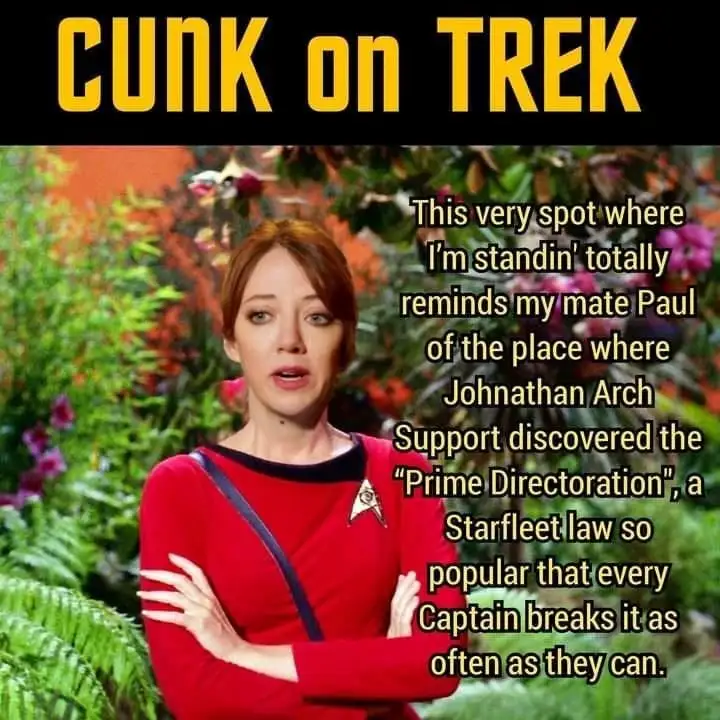 A woman in a red Starfleet uniform stands with arms crossed in a lush garden, looking confused. The image has a black banner…