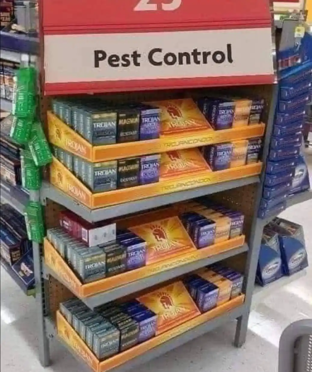 A store shelf labeled 'Pest Control' is stocked with boxes of Trojan condoms, creating a humorous juxtaposition between the…