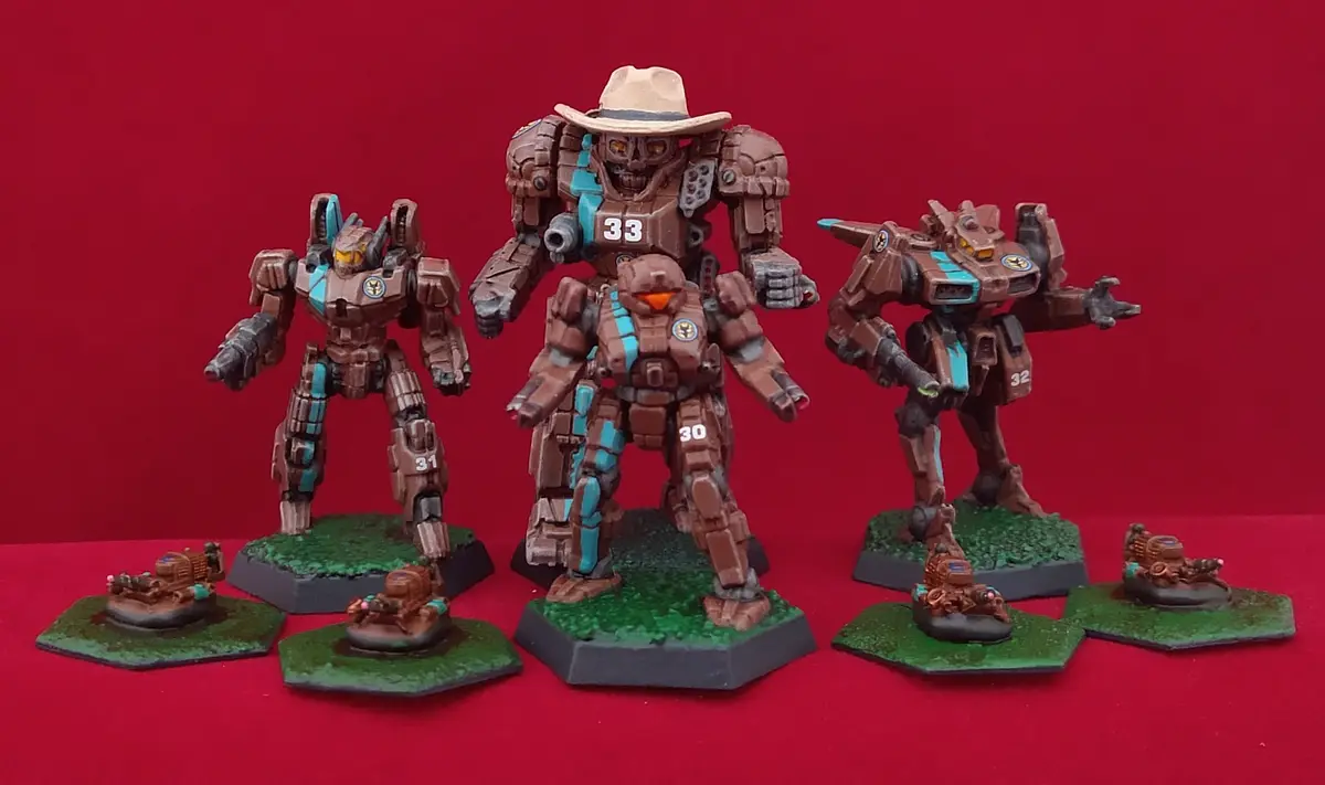 Three brown and teal painted mecha miniatures stand on green bases against a red background, with the central, tallest mech…