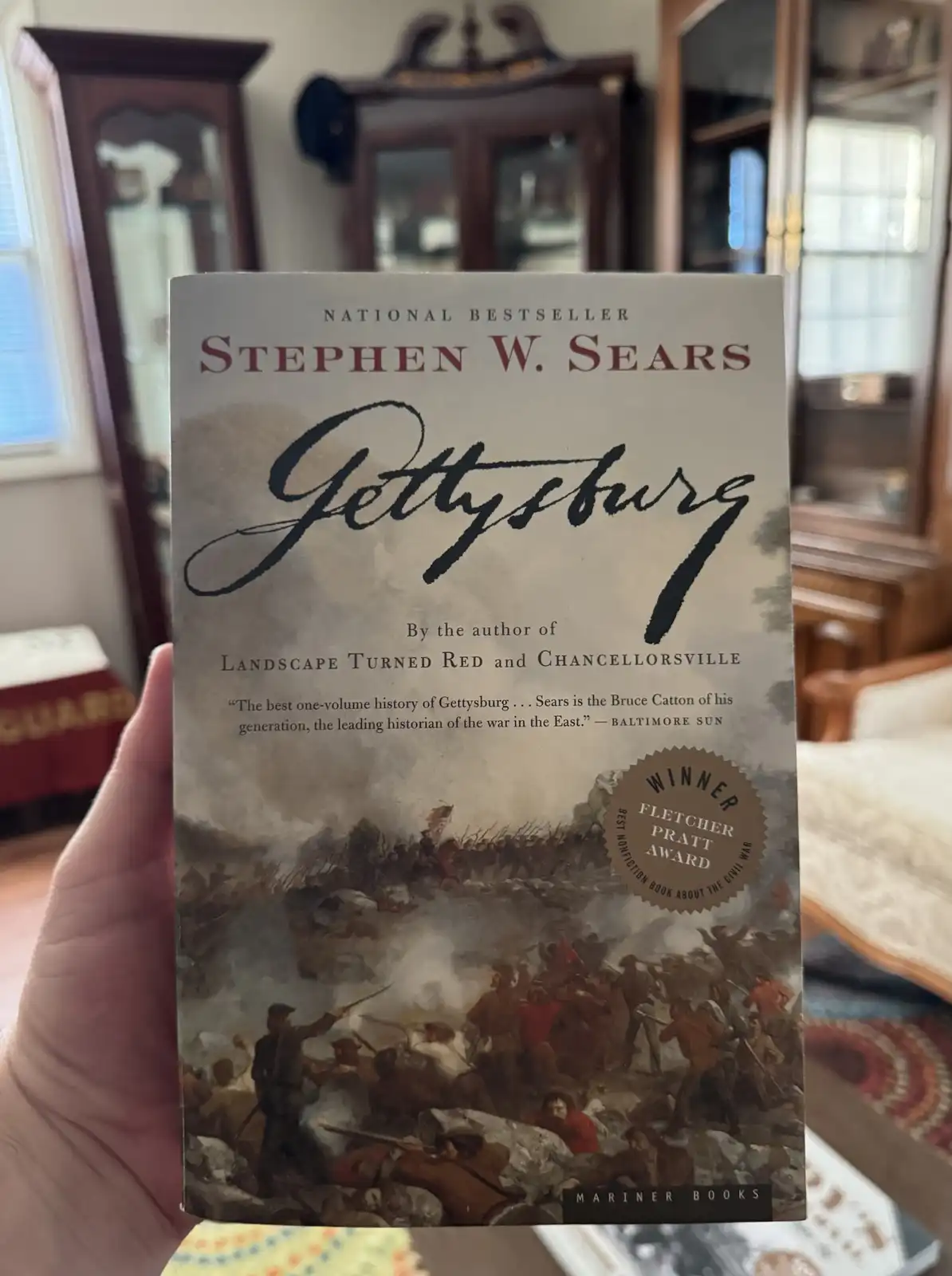 A hand holds up a copy of Stephen W. Sears' book 'Gettysburg,' which features a dramatic painting of the Civil War battle on…