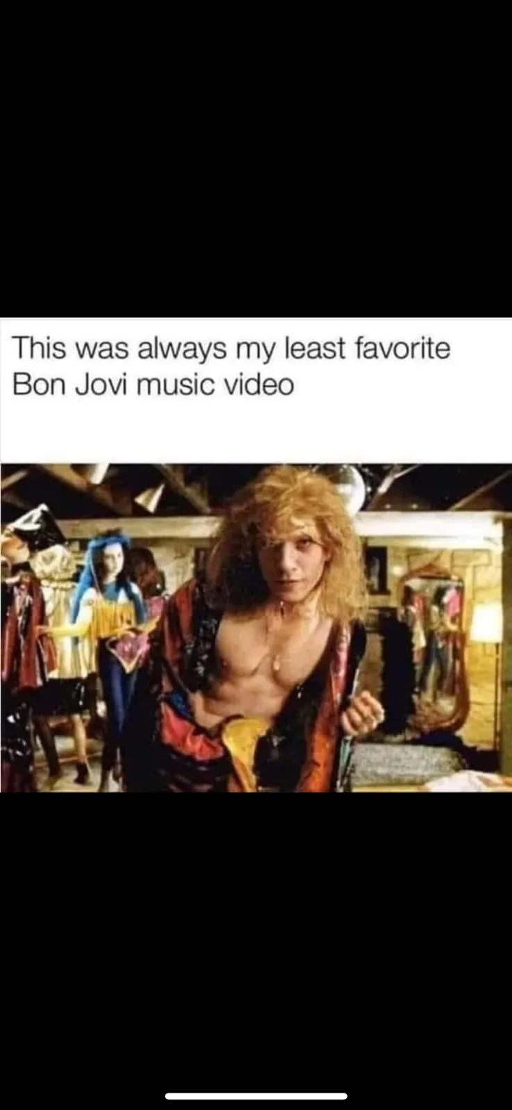 A still from a Bon Jovi music video shows a man with long, curly blonde hair and a partially unbuttoned colorful jacket…
