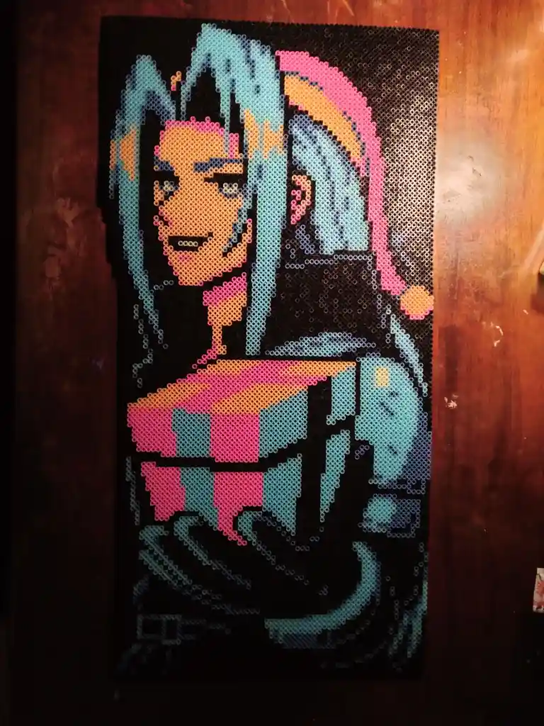 A colorful perler bead artwork depicts a stylized anime-style character with blue and pink hair, wearing a checkered outfit…
