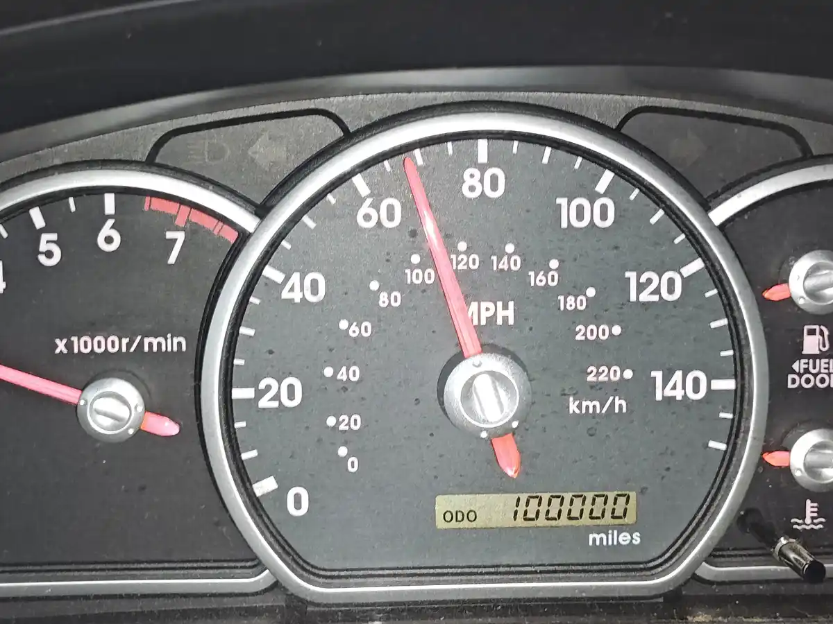 A close-up of a car's dashboard showing a speedometer with the needle at zero, a tachometer with the needle near 7,000 rpm…