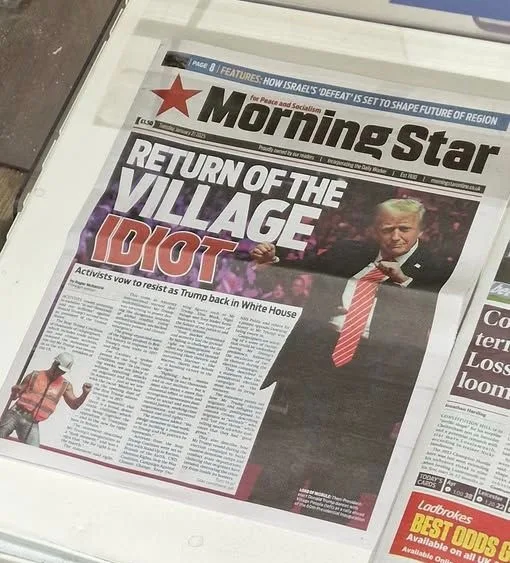 A newspaper front page from the 'Morning Star' features a large headline reading 'RETURN OF THE VILLAGE IDIOT' above a photo…