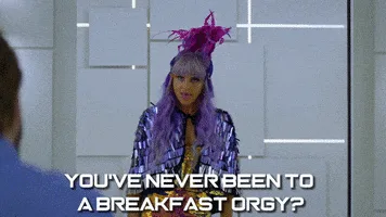 A woman with purple hair and a feathered headpiece, wearing a shiny silver outfit, repeatedly asks the question 'YOU'VE…