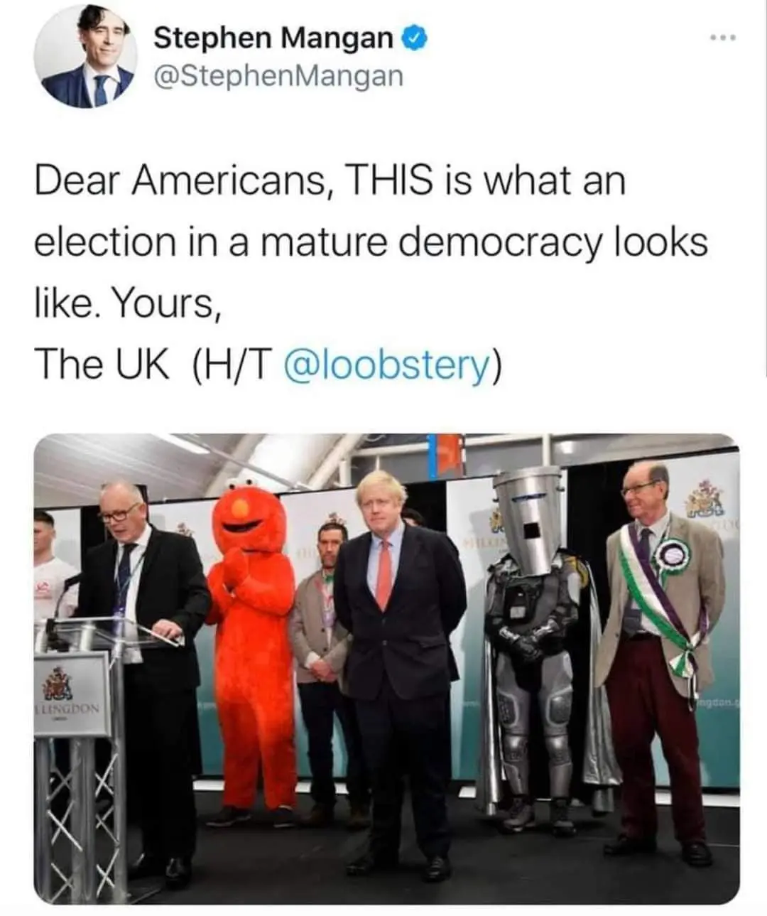 A screenshot of a tweet by Stephen Mangan showing a photo of Boris Johnson standing with several other people, including a…