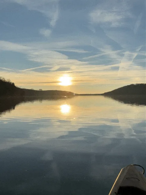 Six identical photos of a serene sunset over a calm lake from a kayak's perspective, with the sun reflecting on the water…