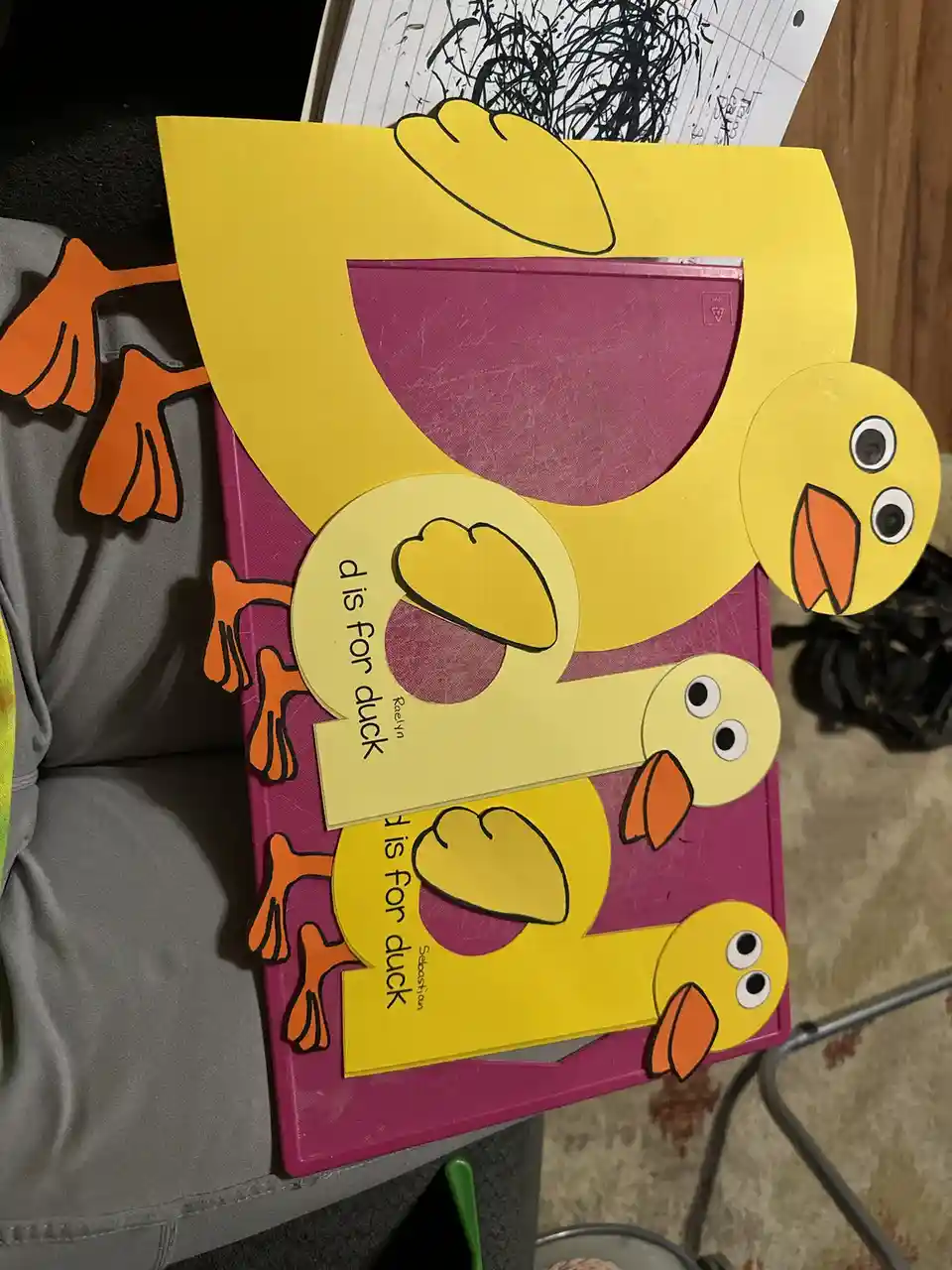 A children's book titled 'd is for duck' is covered with a large, yellow paper cutout shaped like the letter 'D', which has…