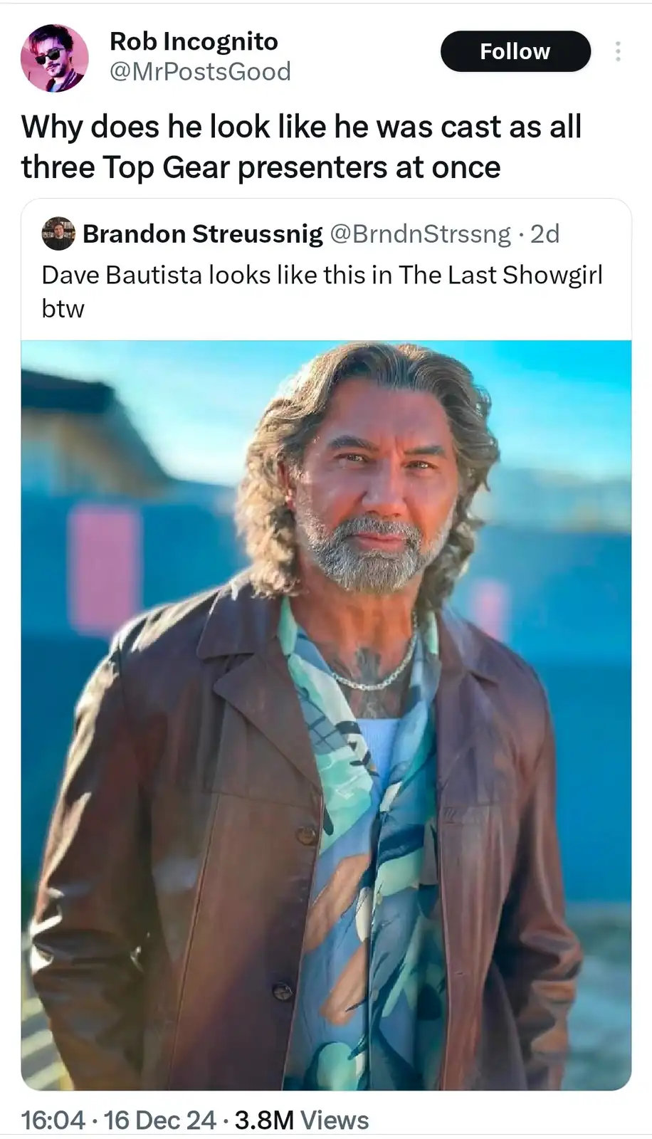 A screenshot of a tweet shows a photo of actor Dave Bautista with long wavy hair, a graying beard, and a tattooed neck…