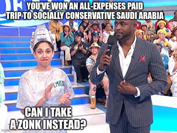 A woman in a silver, sparkly costume with a paper crown and a 'ZONK' tag on her shirt looks dismayed while standing next to…