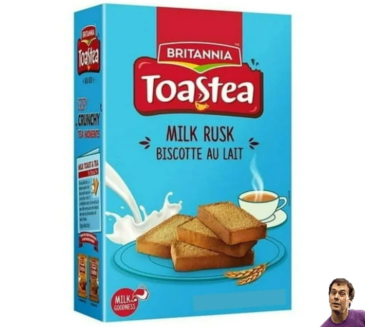 A blue box of Britannia Toastea Milk Rusk biscuits, featuring an image of the biscuits on a plate with a splash of milk and…