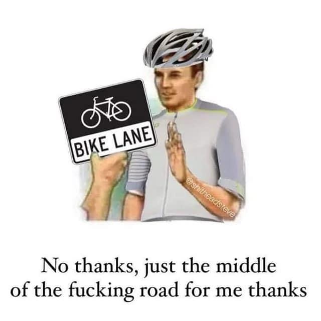 A man wearing a bicycle helmet and cycling jersey holds a 'BIKE LANE' sign in one hand while making a polite but firm 'stop'…