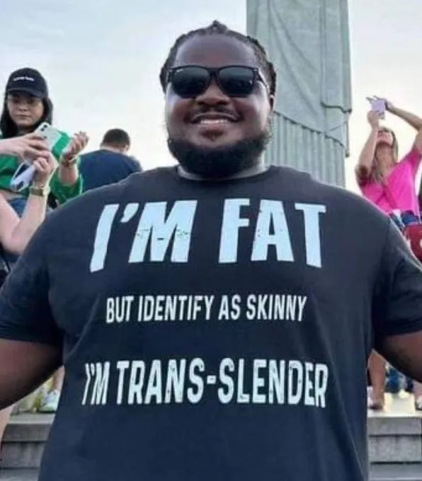 A smiling Black man with sunglasses and a beard wears a black t-shirt with white text that reads 'I'M FAT BUT IDENTIFY AS…