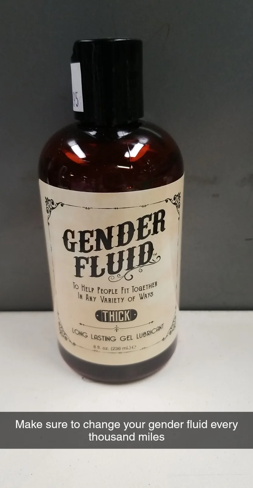 A bottle of amber-colored lubricant with a label that reads 'GENDER FLUID™ To Help People Fit Together In Any Variety of…