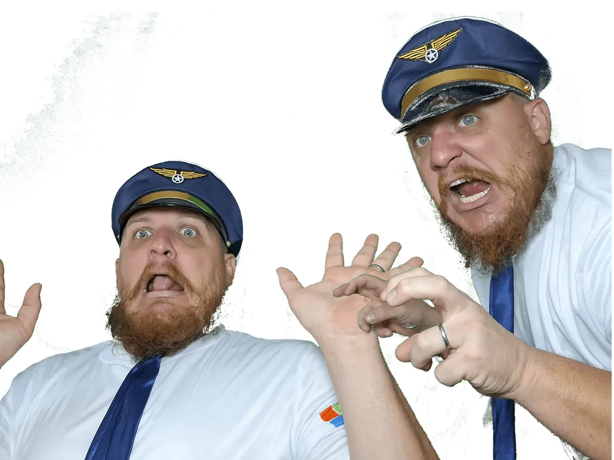 Two men in identical pilot uniforms with blue caps, white shirts, and blue ties are shown against a green background. One…