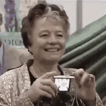 A sequence of six images shows an elderly woman holding a small digital camera. She starts smiling, then brings the camera…