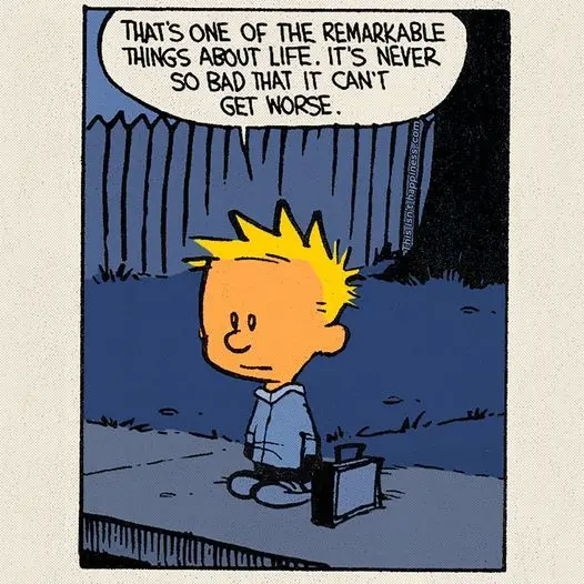 A cartoon boy with spiky yellow hair, wearing a blue shirt and pants, sits on a sidewalk next to a small black suitcase. He…
