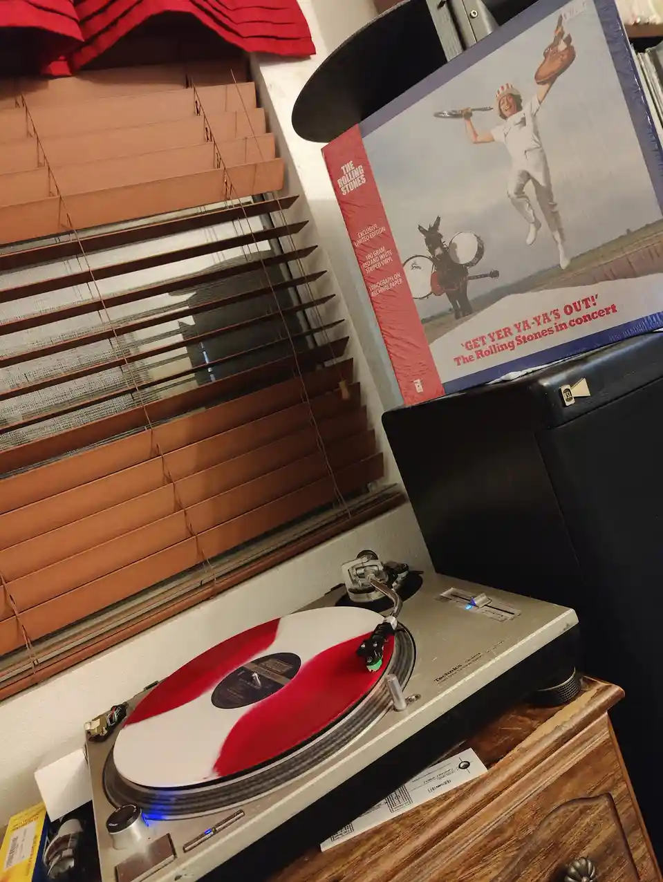 A vintage Technics turntable plays a red and white vinyl record, with the album cover for The Rolling Stones' 'Get Yer…