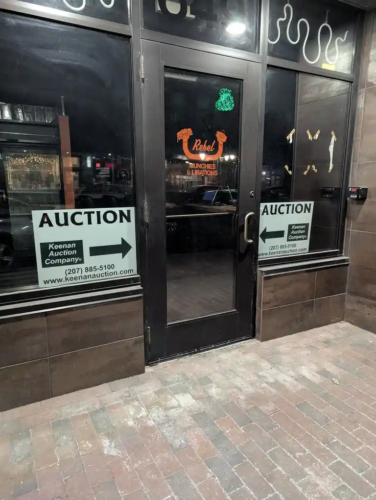 The image shows the entrance to a business named 'Rebel Munchies & Libations' with glass doors and windows. Two identical…