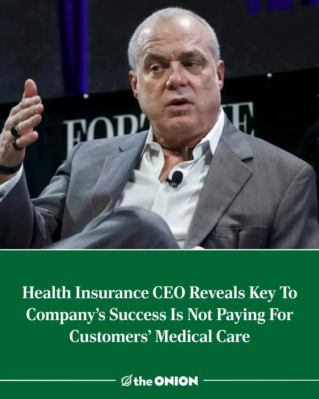 A man in a gray suit and white shirt, gesturing while speaking at what appears to be a 'FORBES' event, has a green banner…