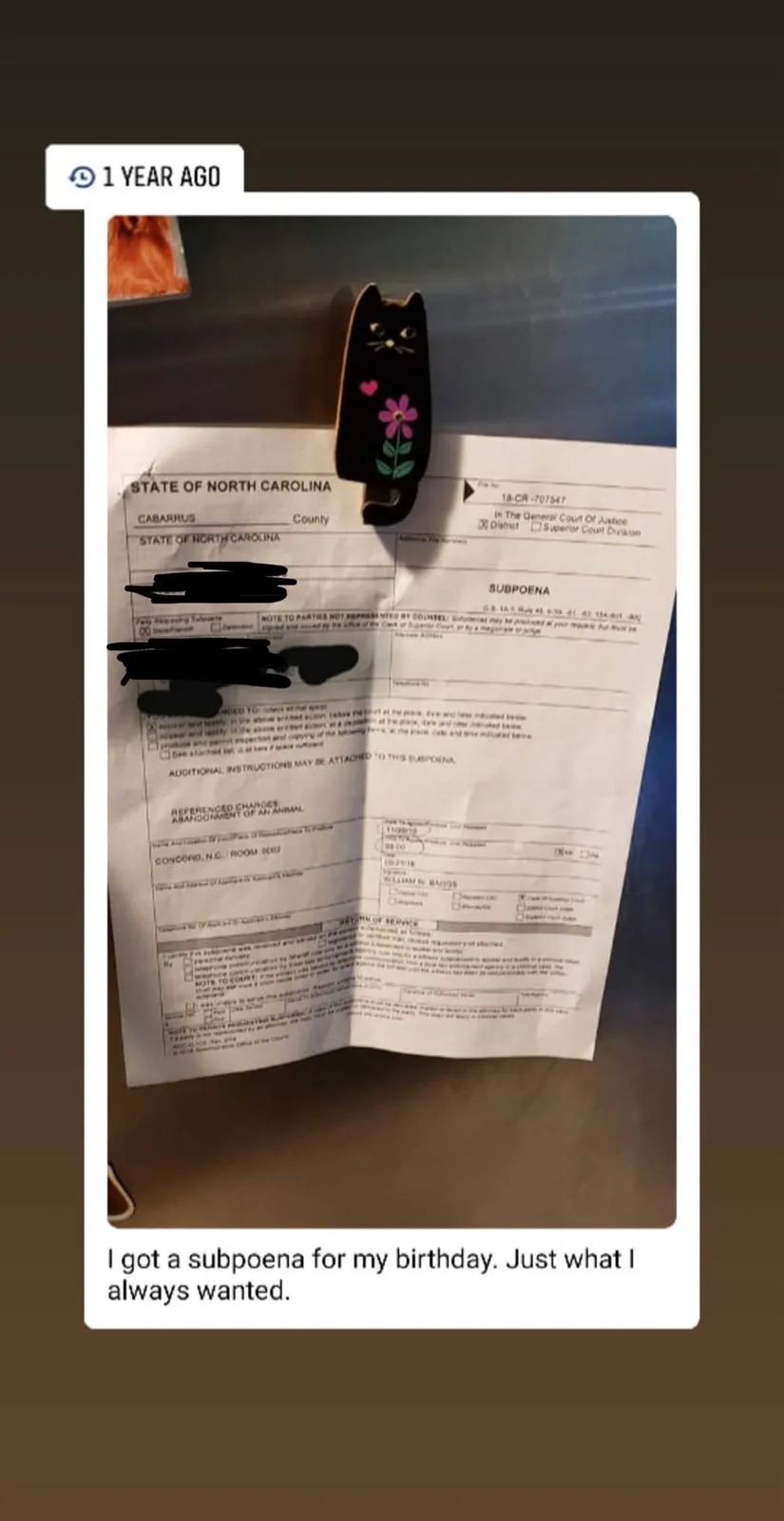 A photo shows a North Carolina subpoena document with personal information redacted, held by a black cat-shaped paperclip…
