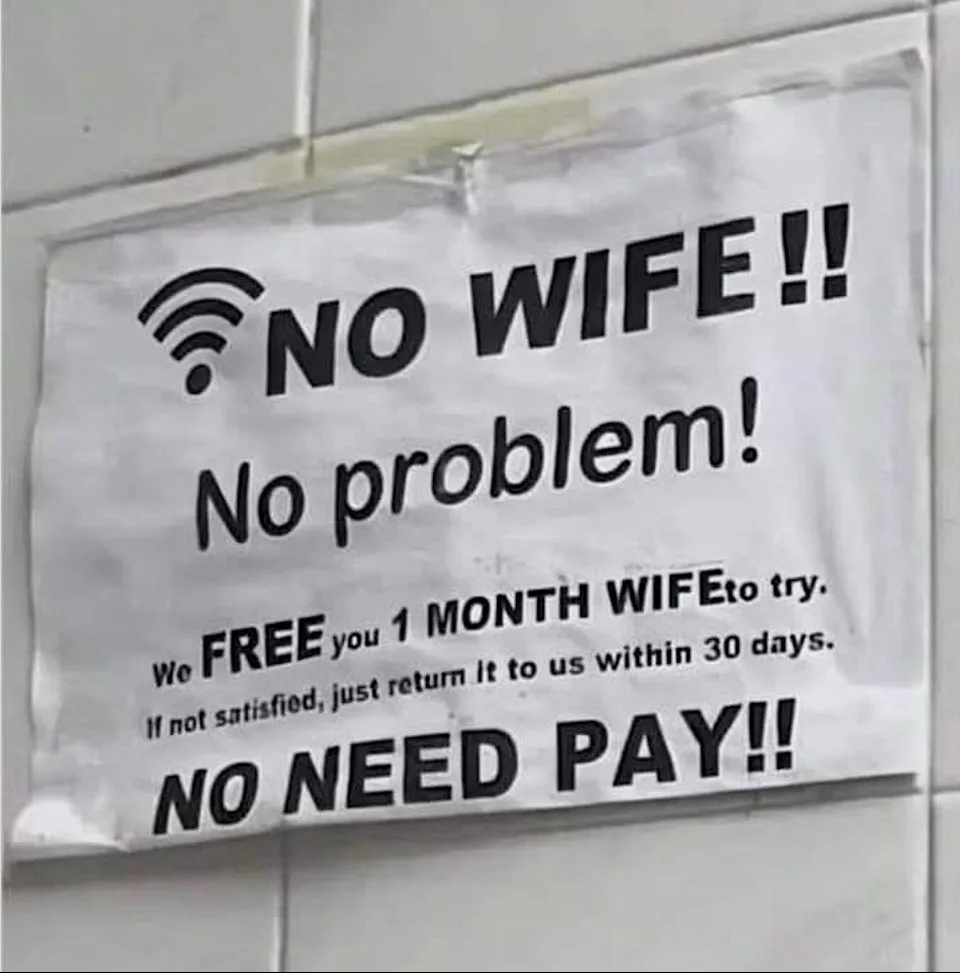 A white paper sign taped to a tiled wall humorously advertises a 'free month of wife' service, using a Wi-Fi symbol to imply…