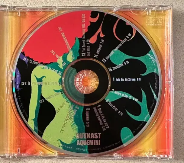 A close-up photo of the OutKast album 'Aquemini' CD, showing its colorful abstract artwork with a green and black…