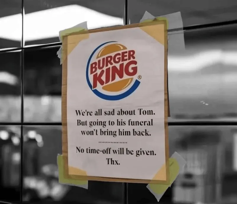 A black-and-white photo shows a Burger King sign taped to a glass door. The sign features the Burger King logo and text…