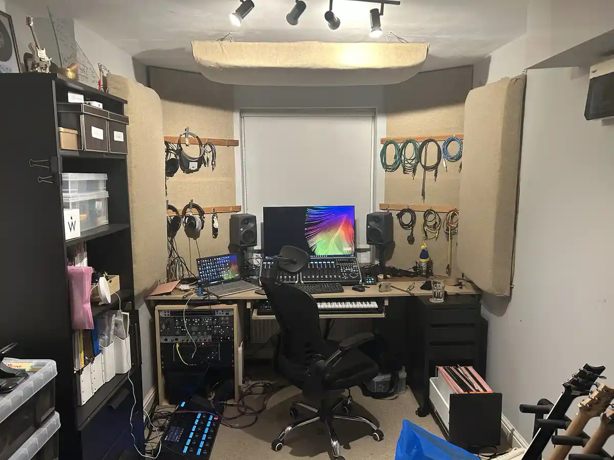 A well-equipped home studio with soundproofing panels on the walls, a desk with a computer, speakers, a keyboard, and a…