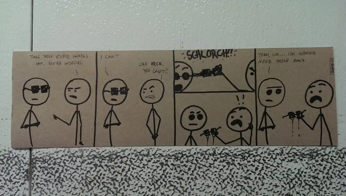 A hand-drawn four-panel comic on cardboard shows a stick figure demanding another stick figure remove their sunglasses…