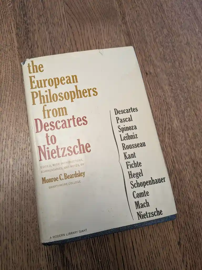 A vintage book titled 'the European Philosophers from Descartes to Nietzsche' by Monroe C. Beardsley rests on a wooden…