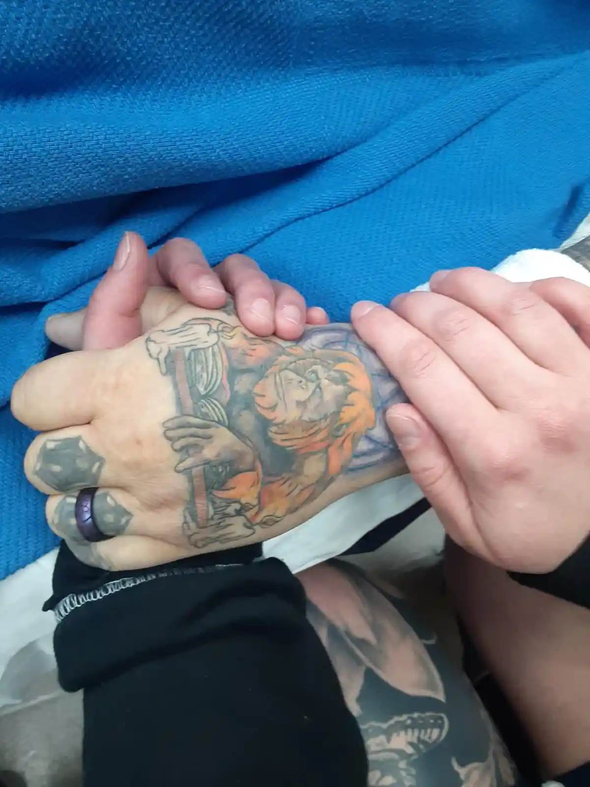A close-up photo shows a person's hand with a detailed tattoo of a monkey holding a sword, partially covered by another…