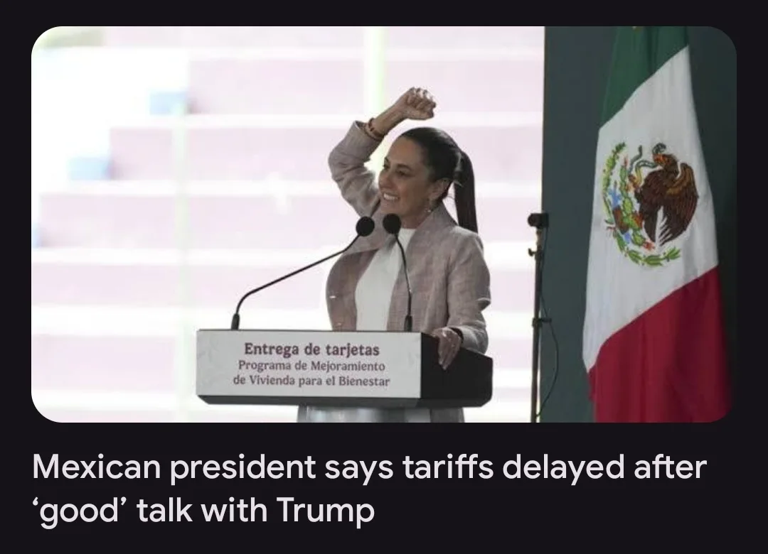 A woman stands at a podium with a Mexican flag to her right, smiling and raising her fist in celebration. The podium has…