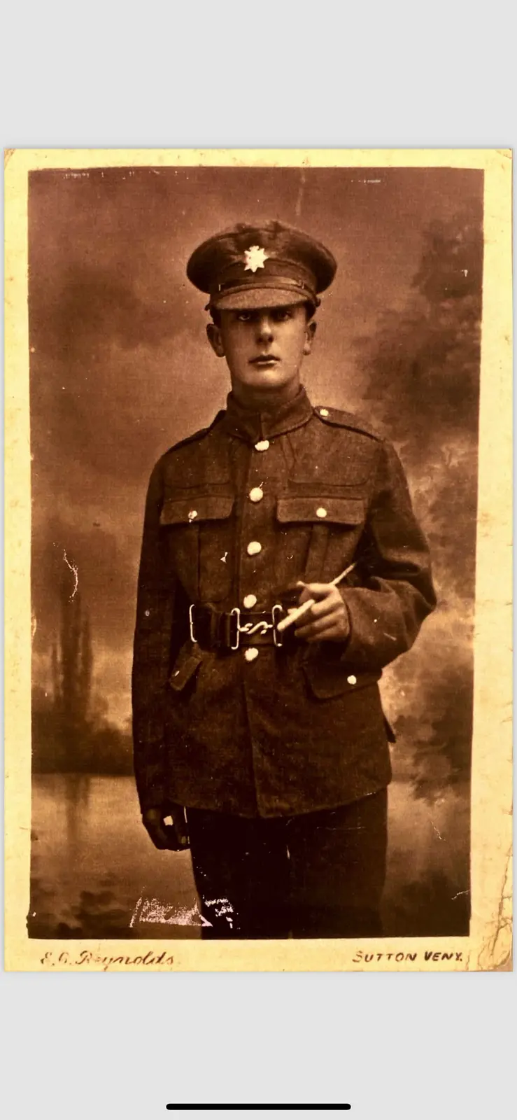 A sepia-toned vintage photograph shows a young man in a military uniform with a star insignia on his cap, holding a…