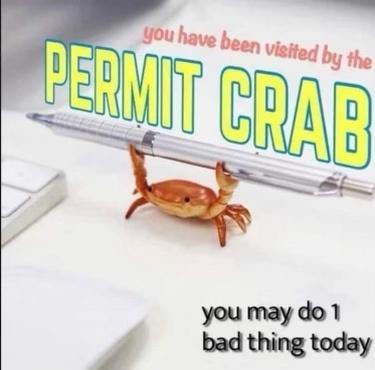 A small orange plastic crab figurine is balancing a silver pen on its back, positioned on a white desk next to a keyboard…