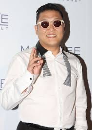A man in a white shirt, patterned necktie, and sunglasses poses with a peace sign while smiling. The overlaid text reads…