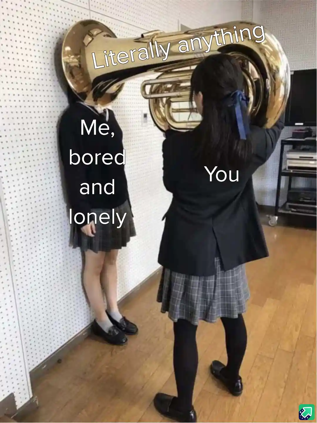 Two schoolgirls in uniforms stand in a room; one holds a large brass tuba, its bell obscuring her face and the text…