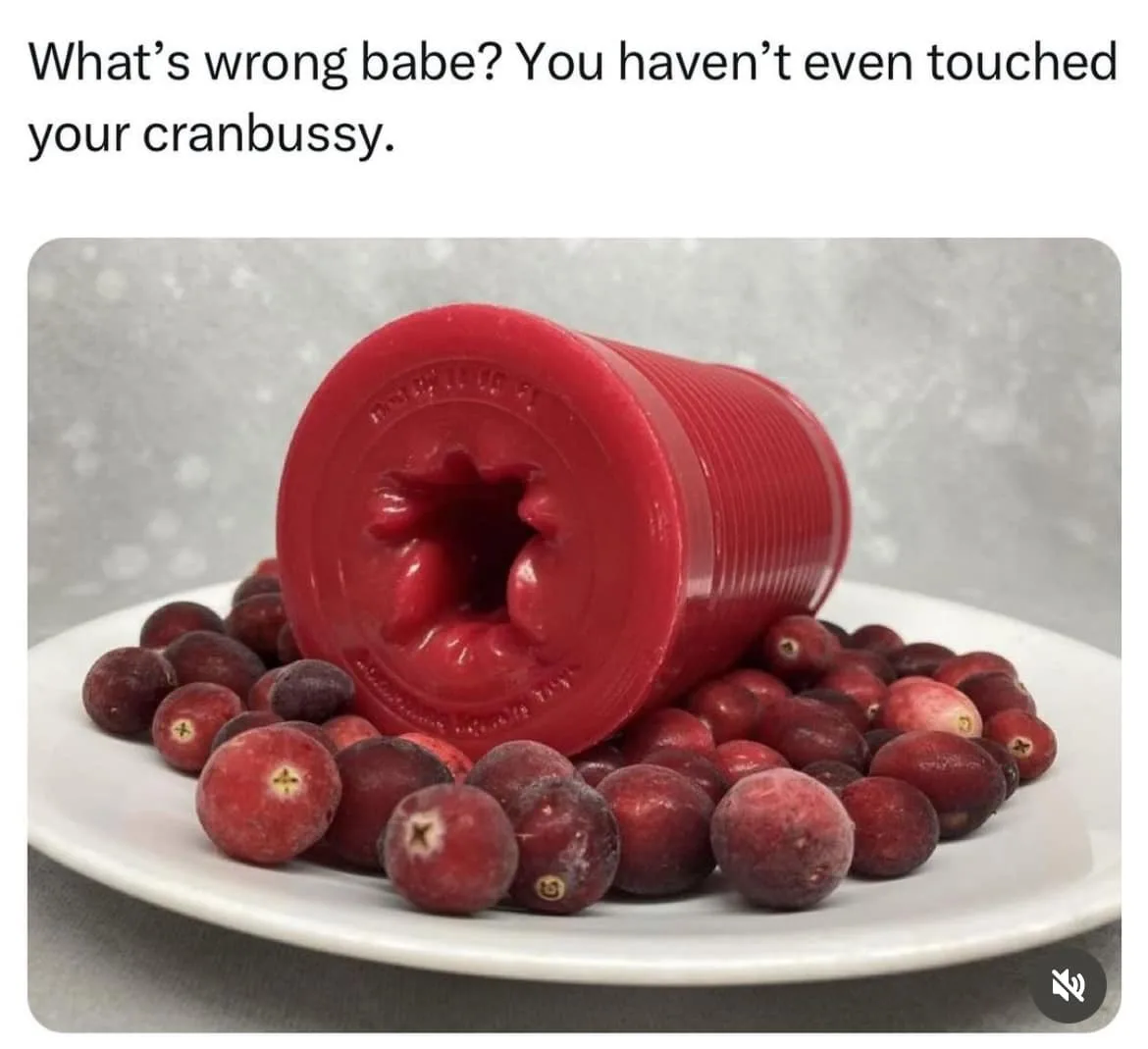 A red, cylindrical, textured object resembling a sex toy is lying on its side on a white plate surrounded by frozen…