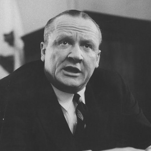 A black-and-white photo of a man in a suit and tie, looking surprised or shocked, with the overlaid text 'I'm not a racist…