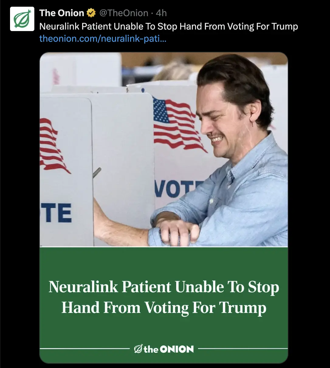 A man in a light blue shirt is smiling while voting at a polling station, with American flag graphics visible on the voting…