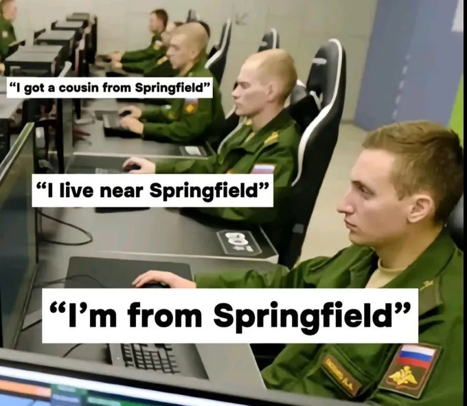 A row of men in green military-style uniforms sit at computer stations in a room. Each man has a white text box overlaid on…