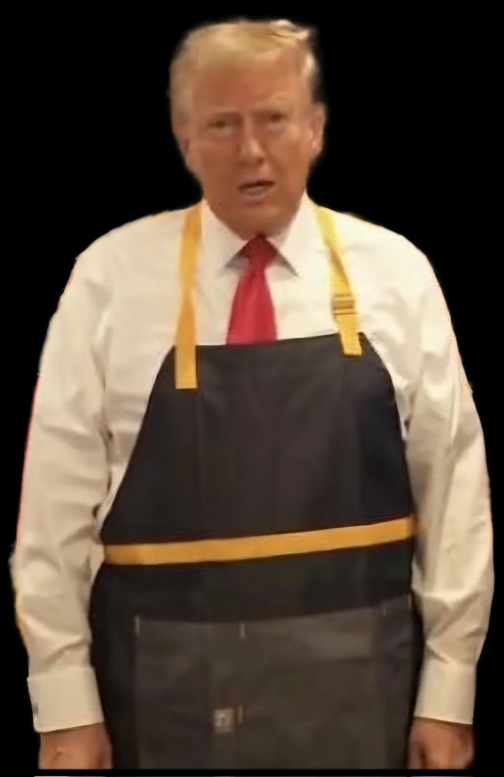 a man with blond hair wearing a white shirt, red tie, and a black apron with yellow straps and trim stands against a black…