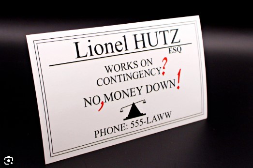 A white business card for 'Lionel HUTZ ESQ' is photographed against a dark background. The card reads 'WORKS ON…