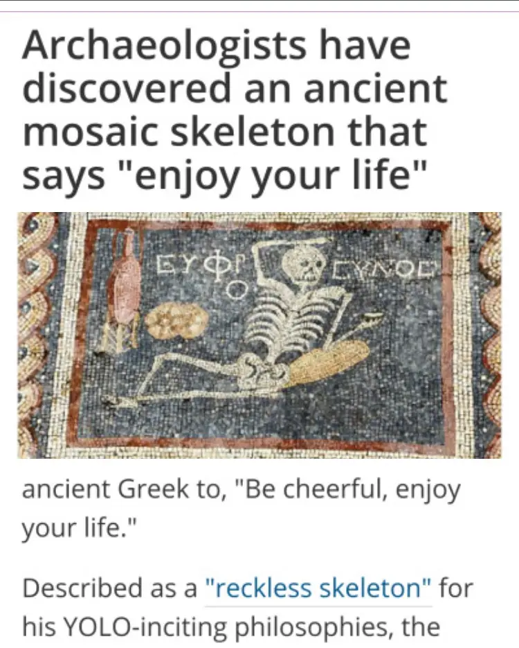 The image shows an ancient mosaic depicting a skeleton reclining, holding a wine jug and a loaf of bread, with Greek text…