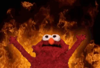 The image shows the red Sesame Street character Elmo standing in front of roaring flames, arms raised in a dramatic, almost…